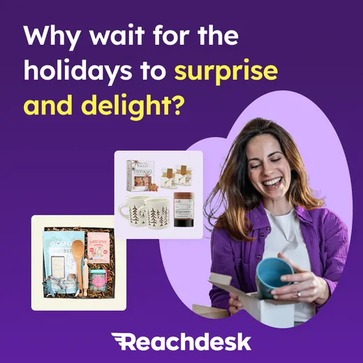 Reachdesk ad on a deep purple background showing a smiling woman lifting a mug out of a gift box with two curated gift boxes beside her, headlined Why wait for the holidays to surprise and delight?